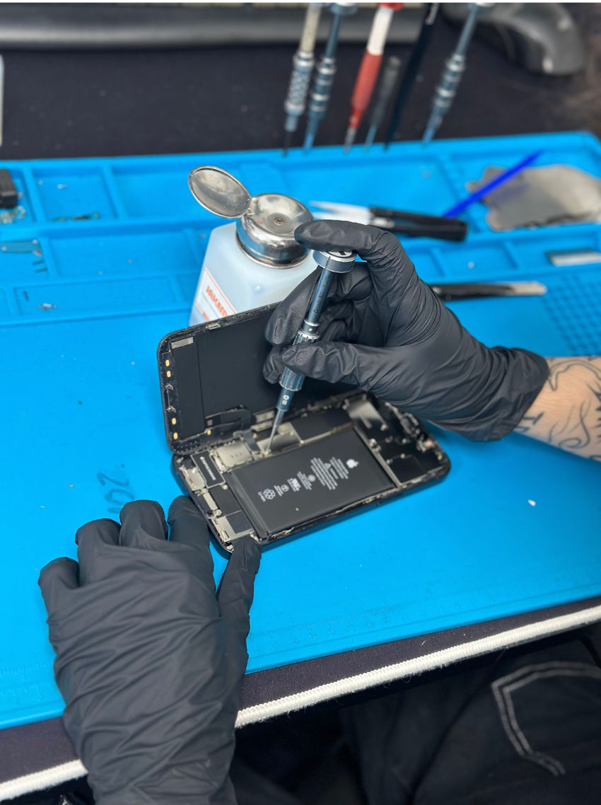 Technicien réparant un smartphone endommagé sur un établi, représentant la prise en charge d’un sinistre téléphonique dans nos locaux à Toulouse.